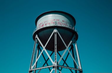 A low angle shot of a water tower with peaceful writings on it on a blue beautiful background